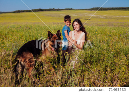Mom and son play with German Shepherd dog on walk 71465583