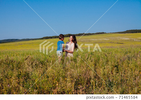 Beautiful woman mom hugs young son in nature on a walk 71465584