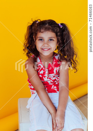 Beautiful little curly cheerful girl with pigtails on a yellow background 71466083