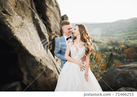 Happy wedding couple posing over beautiful landscape in the mountains Happy wedding couple posing over beautiful landscape in the mountains 71466253