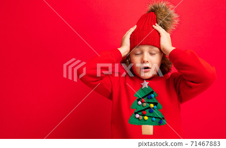 boy model on a red background, portrait of a cool blonde with curls in a sweater with a Christmas boy model on a red background, portrait of a cool blonde with curls in a sweater with a Christmas 71467883