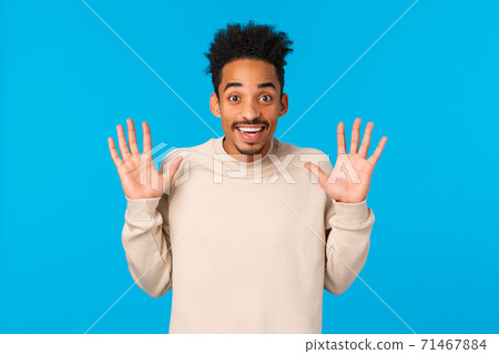 Hey no hands, I got nothing. Cheerful smiling handsome african american boyfriend fooling around, raising palms in surrender gesture, joking express positive emotions, winter concept, blue background 71467884