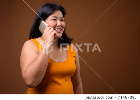 Beautiful overweight Asian woman talking on mobile phone Beautiful overweight Asian woman talking on mobile phone 71467885