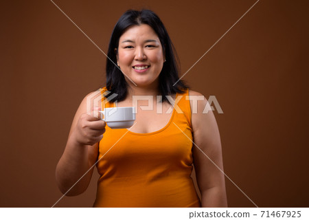 Beautiful overweight Asian woman holding coffee cup 71467925