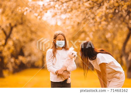 Family of mother and daughter in blooming cherry garden in masks Family of mother and daughter in blooming cherry garden in masks 71468162