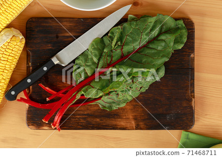 Bunch of beet leaves on wooden cutting board and knife on table 71468711