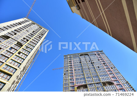 Tower cranes working at construction site on blue sky background. Tower cranes working at construction site on blue sky background. 71469224