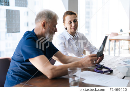 Professional doctor and nurse examining together history disease of patient using MRI scan of head 71469420