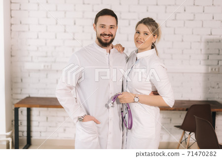 Portrait of smiling man and woman wearing white coats, looking at camera 71470282