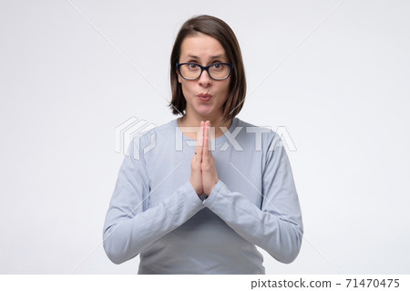 Mature woman wearing glasses keeps palms together, has pleased expression Mature woman wearing glasses keeps palms together, has pleased expression 71470475