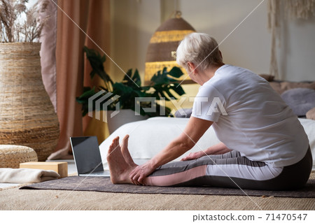 Sporty senior woman practicing yoga, doing seated forward bend pose, paschimothanasana 71470547