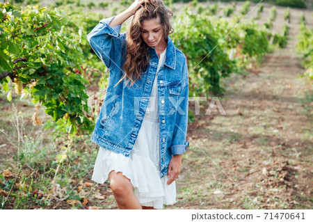 Beautiful woman collects grapes in a vineyard Beautiful woman collects grapes in a vineyard 71470641