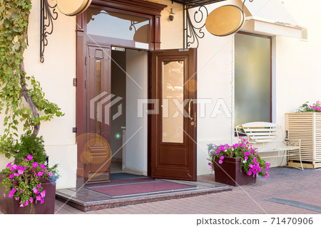 entrance door with a threshold and mat on the facade of the building with a flowerpot, european cityscaep nobody. 71470906