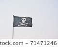 Pirate flag with with skull and bones on a light blue sky background. 71471246