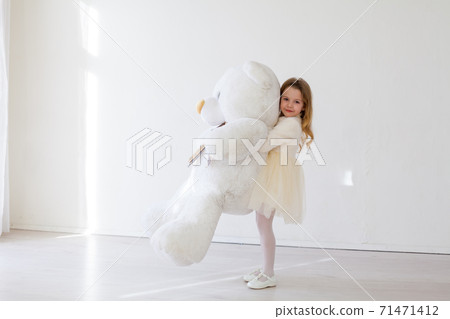 Beautiful little girl holding a white teddy bear toy 71471412