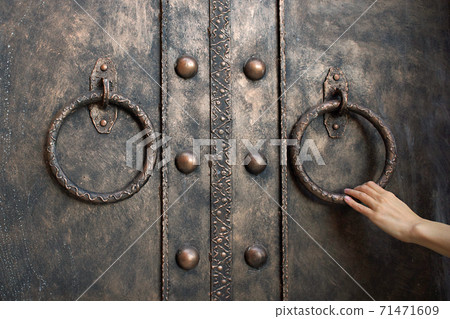 Closeup photo of elegant woman's hand holding metal ring of iron entrance door on brick wall Closeup photo of elegant woman's hand holding metal ring of iron entrance door on brick wall 71471609