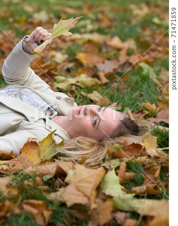 Young Woman Laying in the Grass in Autumn Park Young Woman Laying in the Grass in Autumn Park 71471859