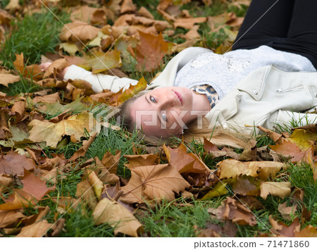 Young Woman Laying in the Grass in Autumn Park Young Woman Laying in the Grass in Autumn Park 71471860