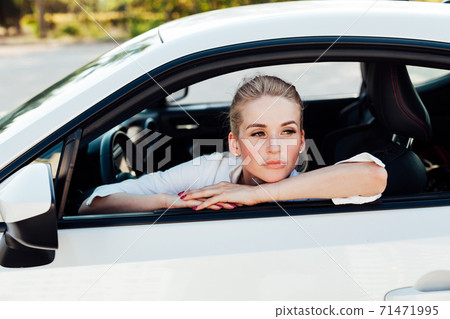 Beautiful female blonde driver behind the wheel of a car on the road Beautiful female blonde driver behind the wheel of a car on the road 71471995