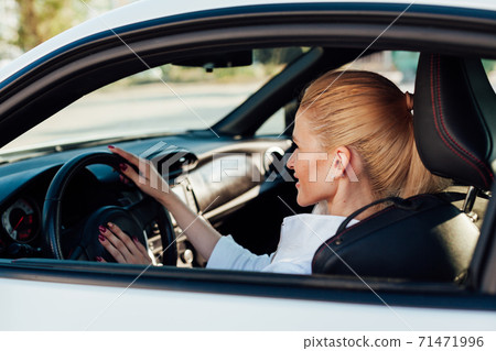 Beautiful female blonde driver behind the wheel of a car on the road Beautiful female blonde driver behind the wheel of a car on the road 71471996