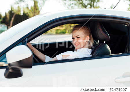 Beautiful female blonde driver behind the wheel of a car on the road Beautiful female blonde driver behind the wheel of a car on the road 71471997