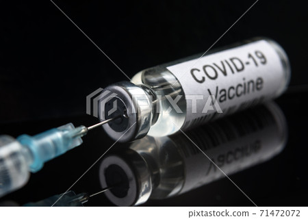 COVID-19 coronavirus vaccine on black, syringe and bottle close-up 71472072