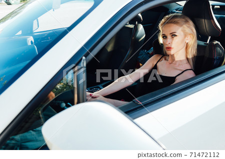 Beautiful fashionable woman blonde driver behind the wheel of a car Beautiful fashionable woman blonde driver behind the wheel of a car 71472112