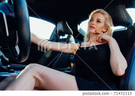 Beautiful fashionable woman blonde driver behind the wheel of a car Beautiful fashionable woman blonde driver behind the wheel of a car 71472113