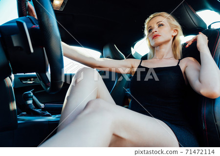 Beautiful fashionable woman blonde driver behind the wheel of a car 71472114