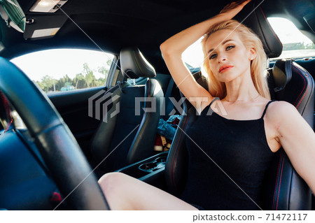 Beautiful fashionable woman blonde driver behind the wheel of a car Beautiful fashionable woman blonde driver behind the wheel of a car 71472117