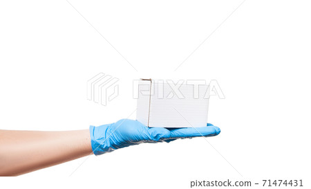 Delivery man hand in blue sterile latex glove demonstrate white label cardboard box on palm, safe delivery during quarantine stay home, isolated on white background with copy space. Delivery man hand in blue sterile latex glove demonstrate white label cardboard box on palm, safe delivery during quarantine stay home, isolated on white background with copy space. 71474431