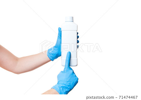 plastic white bottle for sanitizer in hand with a blue medical sterile glove points a finger at unlabel bottle with a place for text, object isolated on white background with copy space. plastic white bottle for sanitizer in hand with a blue medical sterile glove points a finger at unlabel bottle with a place for text, object isolated on white background with copy space. 71474467