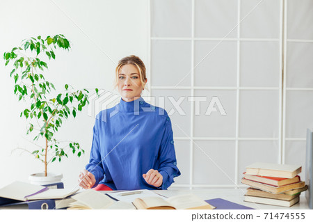 woman in business suit at work in office at a desk with books and documents accountant 71474555