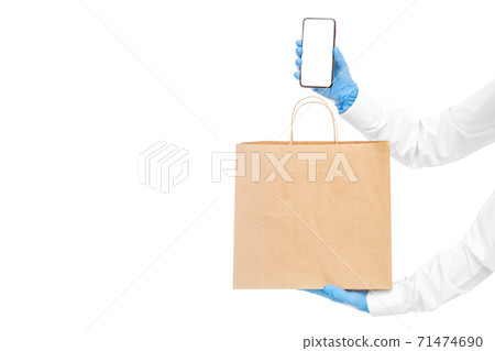 faceless delivery man hold in hands brown paper eco friendly package and cell phone in sterile glove isolated on white with copy space, safe online delivery social distance, stay home. faceless delivery man hold in hands brown paper eco friendly package and cell phone in sterile glove isolated on white with copy space, safe online delivery social distance, stay home. 71474690