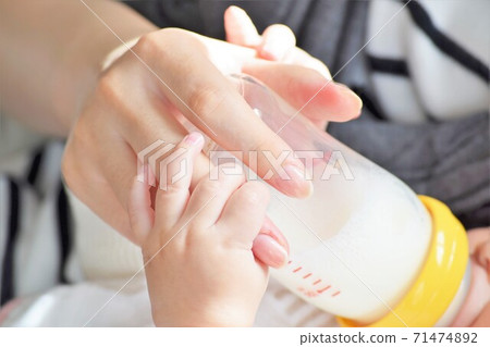 母親的手喝牛奶,嬰兒的小可愛手握住那隻手 母親的手喝牛奶,嬰兒的小可愛手握住那隻手 71474892