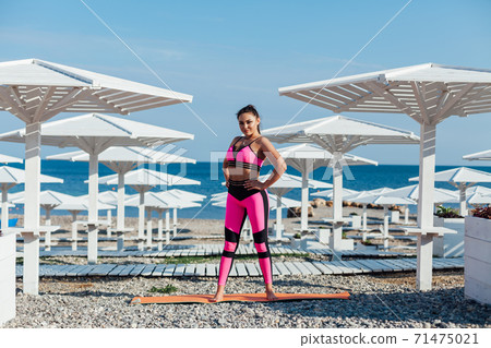 Brunette woman in sportswear sports fitness workout yoga on the beach by the sea Brunette woman in sportswear sports fitness workout yoga on the beach by the sea 71475021