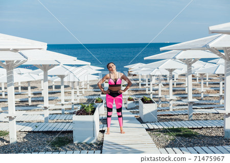 Beautiful woman engaged in fitness yoga gymnastics on the beach by the sea Beautiful woman engaged in fitness yoga gymnastics on the beach by the sea 71475967