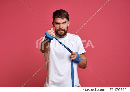 man in white t-shirt ties his hand with a bandage martial arts pink background man in white t-shirt ties his hand with a bandage martial arts pink background 71476711