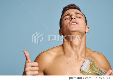 naked man with a massage instrument in his hand on a blue background emotions open mouth model naked man with a massage instrument in his hand on a blue background emotions open mouth model 71476974