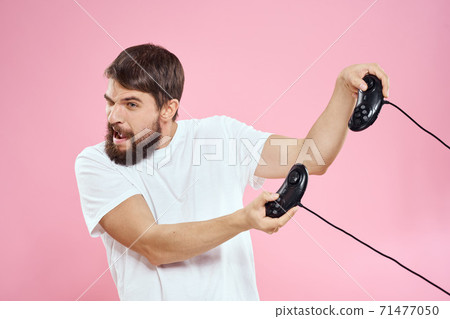 Man with two joysticks in hands fun game technology lifestyle pink background Man with two joysticks in hands fun game technology lifestyle pink background 71477050