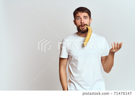 Cheerful man with a banana in his hands on a light background fun emotions Cropped view Copy Space Cheerful man with a banana in his hands on a light background fun emotions Cropped view Copy Space 71478147