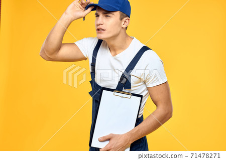 Man in working uniform documents rendering of services delivery service yellow background Man in working uniform documents rendering of services delivery service yellow background 71478271