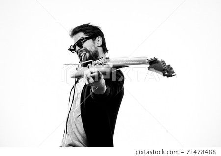 A man holds a guitar in his hands black leather jacket dark glasses music performance light background A man holds a guitar in his hands black leather jacket dark glasses music performance light background 71478488