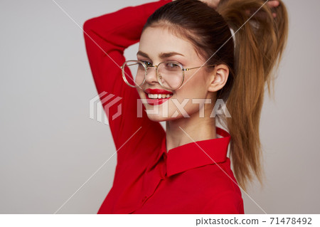fashionable woman in a red shirt on a light background fun emotions bright makeup glasses attractive appearance fashionable woman in a red shirt on a light background fun emotions bright makeup glasses attractive appearance 71478492