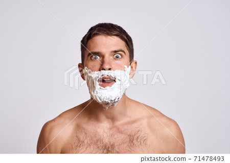 Handsome man with white shaving foam on his face and clean skin with razor grooming bare shoulders Handsome man with white shaving foam on his face and clean skin with razor grooming bare shoulders 71478493