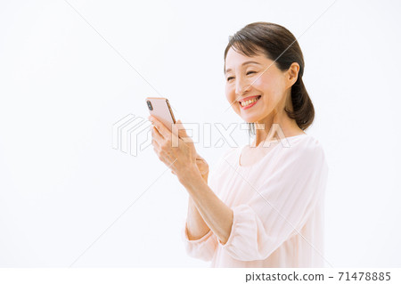 Senior woman with a smartphone smiles 71478885
