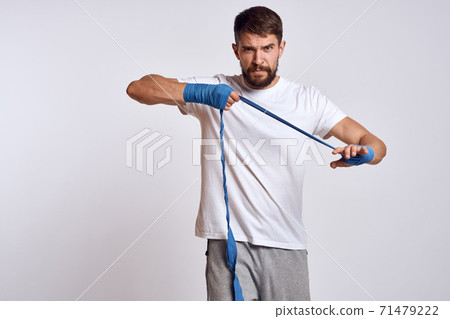 sports man in white t-shirt blue boxing bandages on his arms workout exercises 71479222