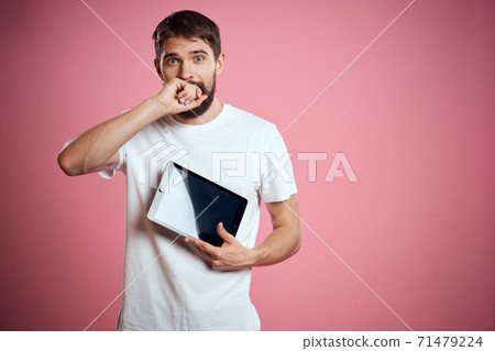 Man advertises a tablet on a pink background codes Space cropped view of emotions white t-shirt model new technologies Man advertises a tablet on a pink background codes Space cropped view of emotions white t-shirt model new technologies 71479224