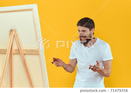 Male artist stands in front of easel emotions drawing Creative approach yellow Male artist stands in front of easel emotions drawing Creative approach yellow 71479356