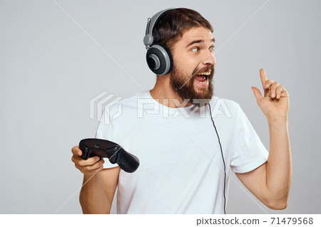Man in headphones with gamepad playing hobby entertainment lifestyle light background 71479568